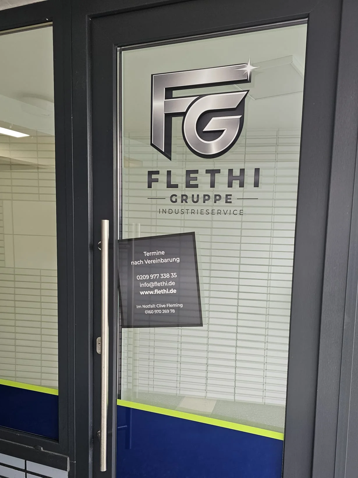 Eingangstür der Flethi Gruppe in Herten mit dem Firmenlogo auf der Glasscheibe